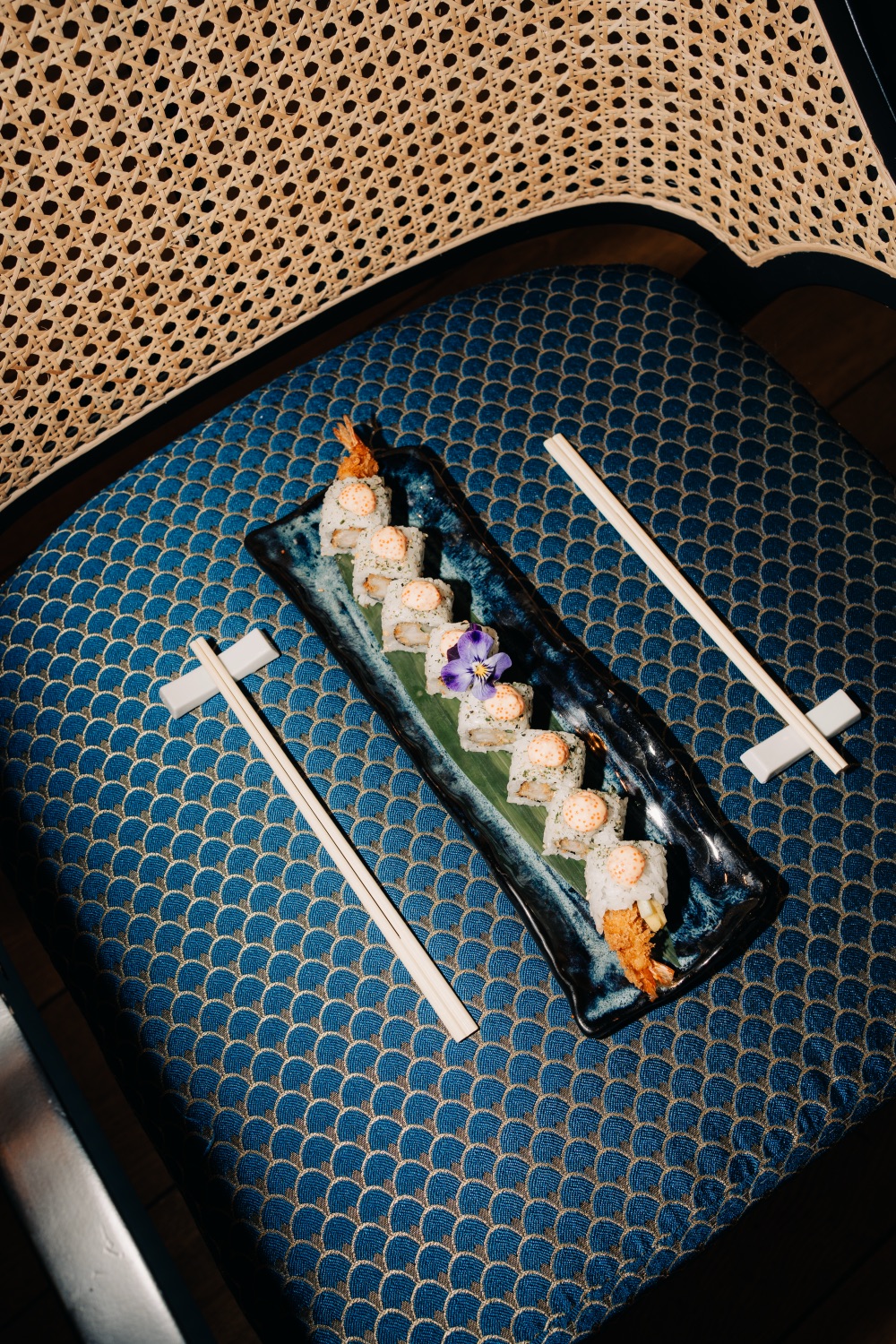 Sushi rolls op een blauw patroon met stokjes ernaast