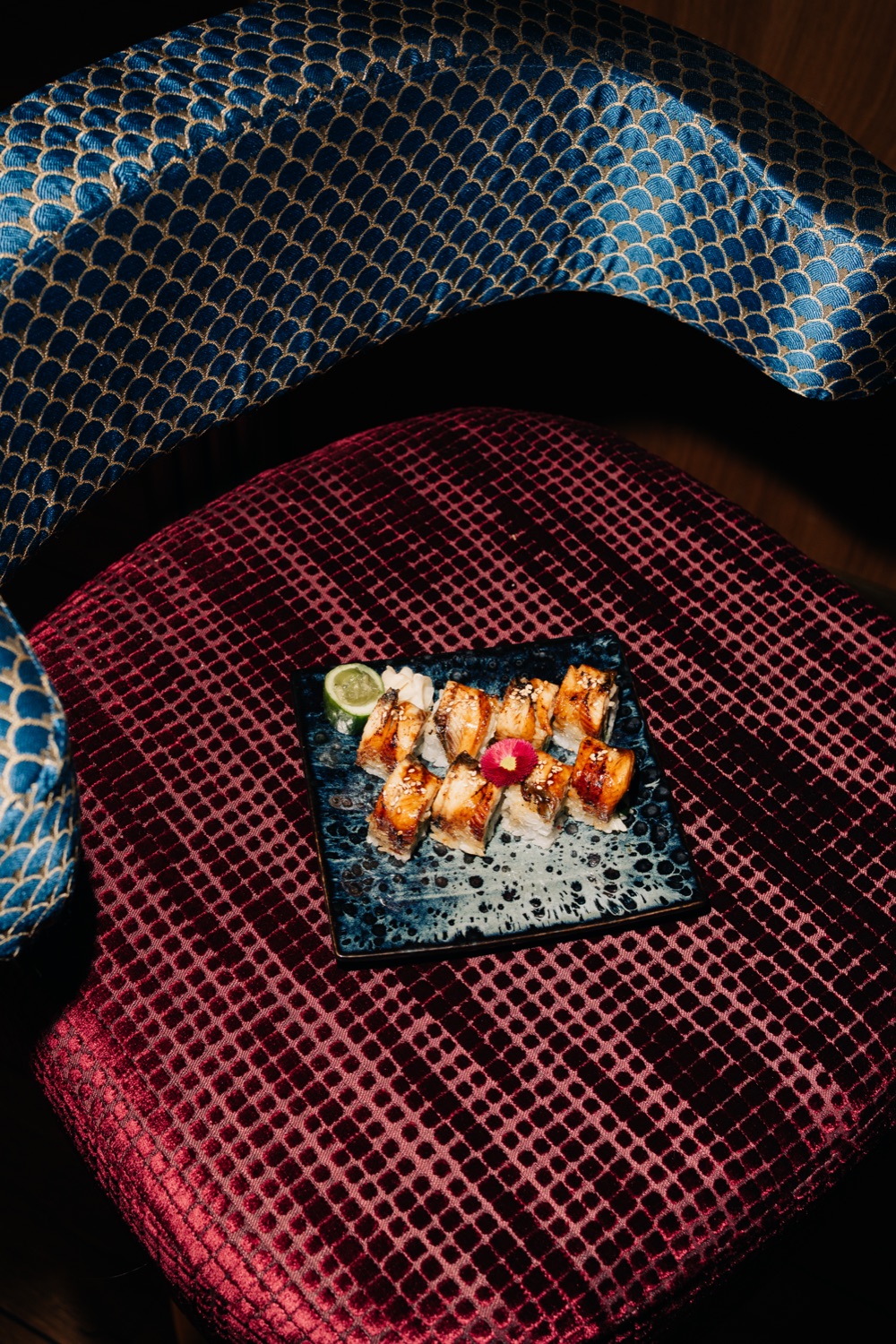 Paling-sushi op een blauw bord op een rood fluwelen stoel
