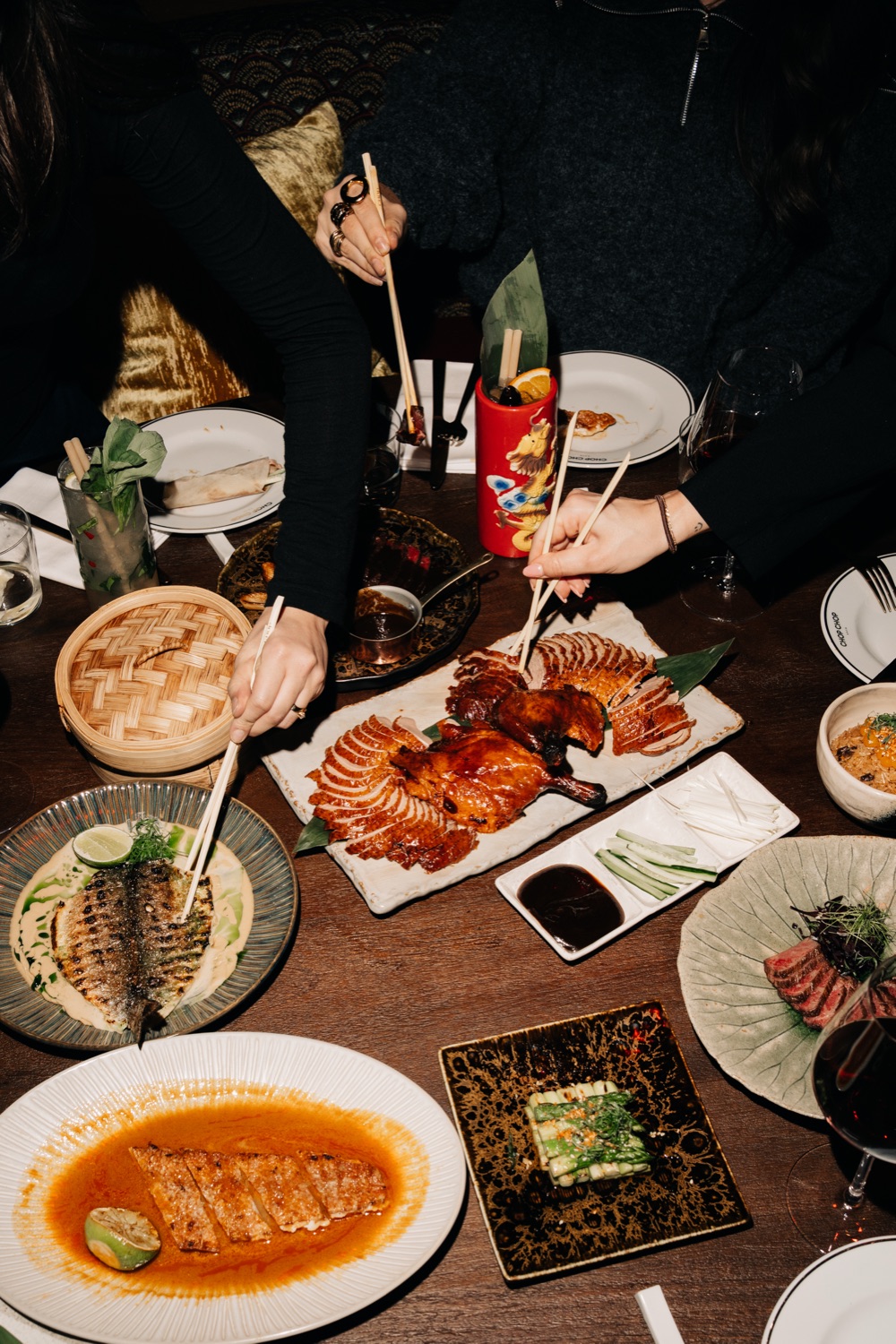 Gasten delen Peking duck en andere gerechten met stokjes aan tafel
