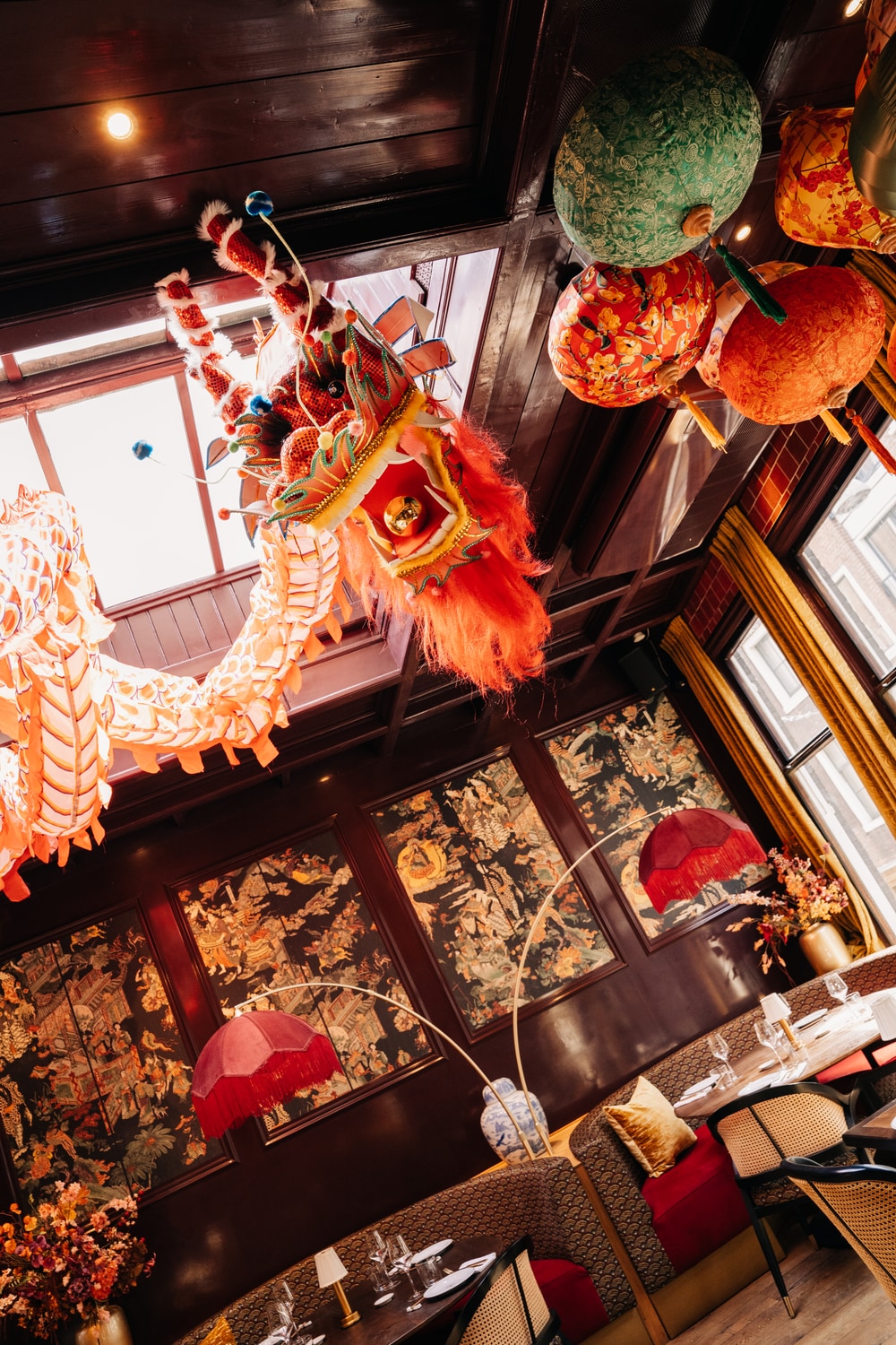 De eetzaal van bovenaf, met een papieren draak en lampionnen aan het plafond