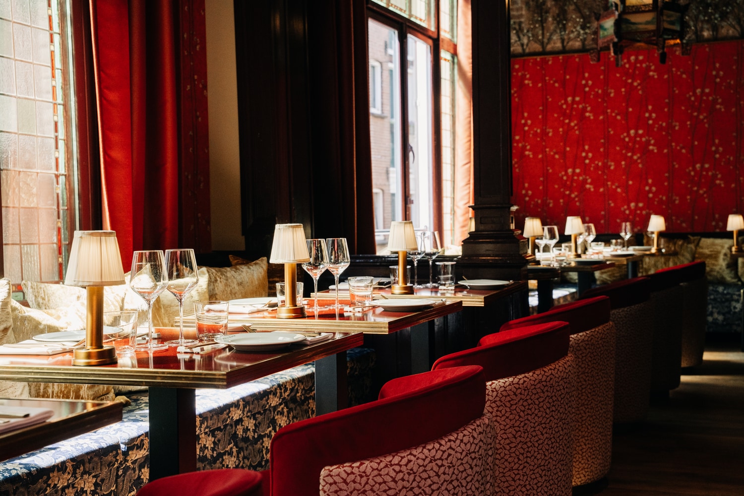 Eetzaal met rood fluwelen banken en gedekte tafels langs de ramen
