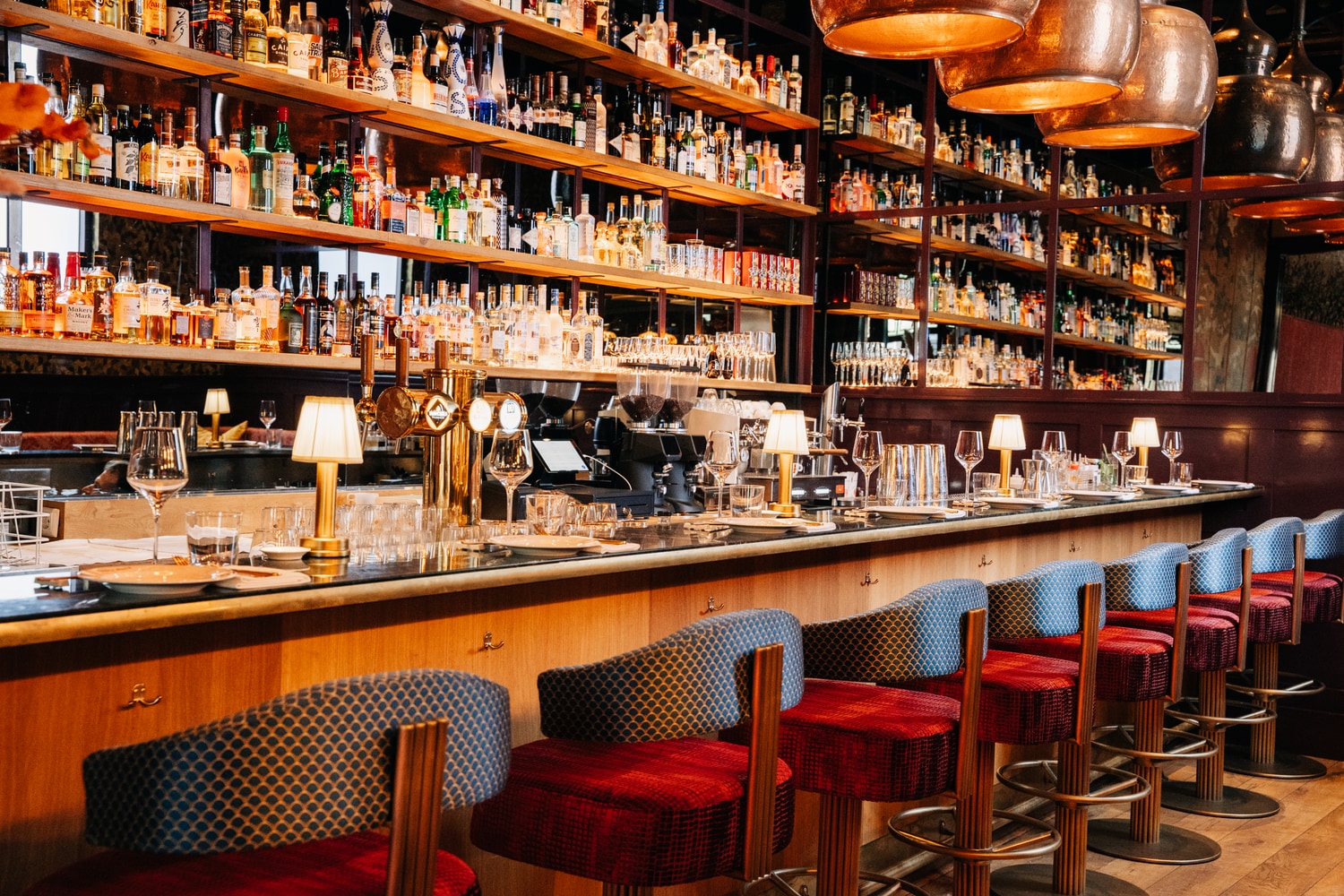 The back bar stocked with bottles, stools running the length of the counter